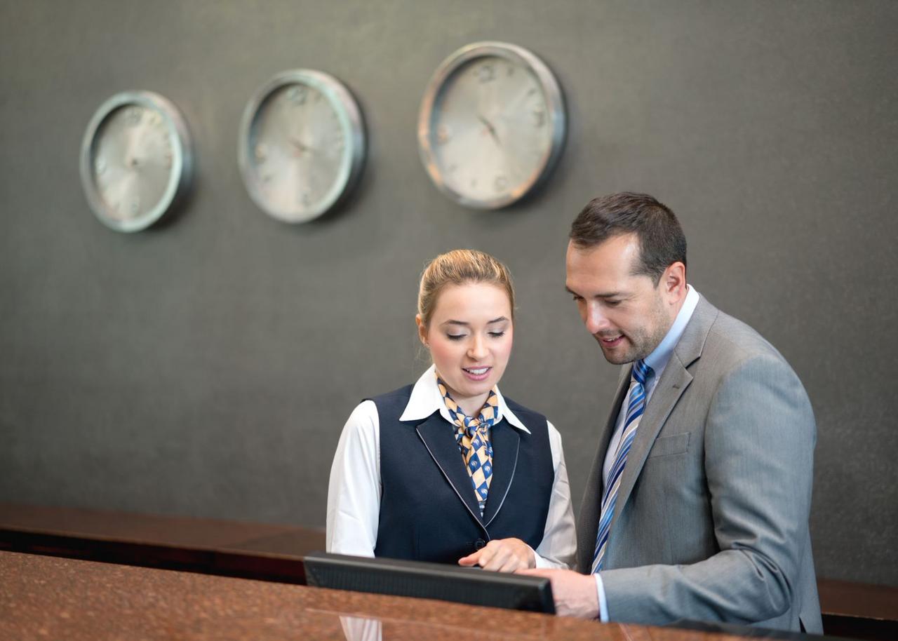 Two people looking at something with 3 clocks in background